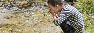 Niño bebiendo agua de un río